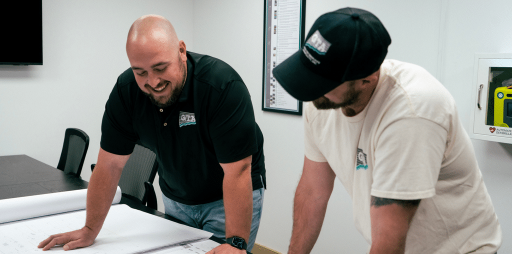 image 3 - Geo-Technology Associates, Inc. Two gta employees looking down at project details on a table